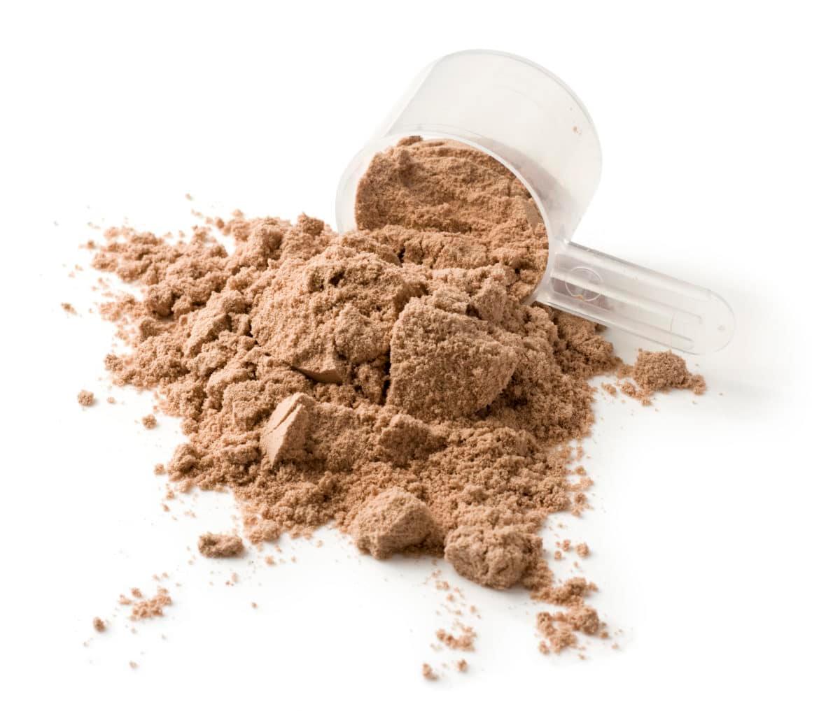 Brown insect powder in a clear measuring scoop on a white surface.