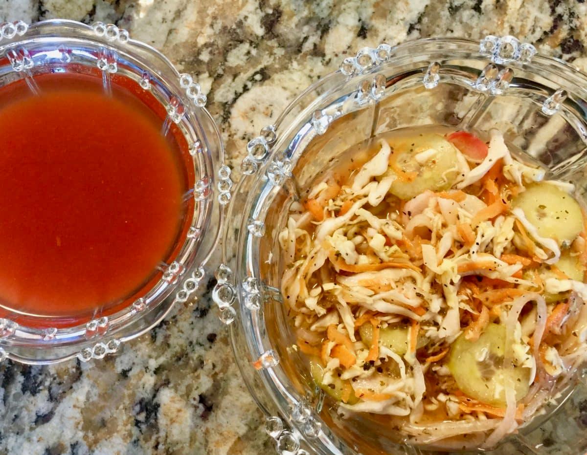 Two glass bowls on granite countertop; one bowl of tomato sauce, one bowl of curtido
