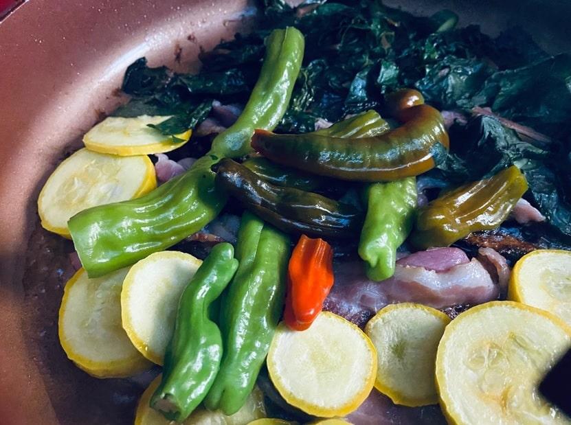 Pan filled with fried Shishito peppers stuffed and accompanied by sliced vegetables.