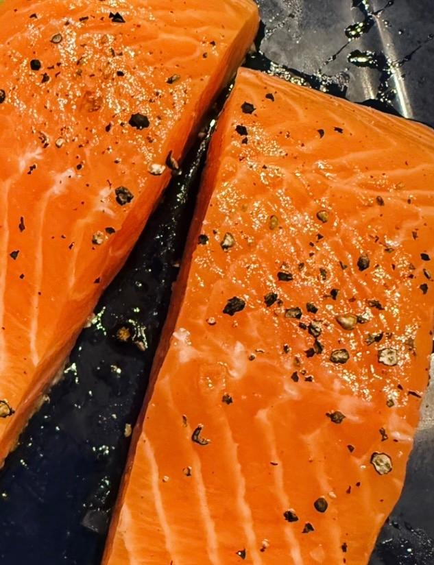 Lightly smoked salmon with salt and pepper, ready to be cooked.